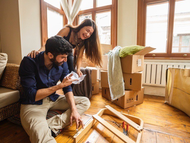 Two people looking in a home surrounded by furniture and boxes