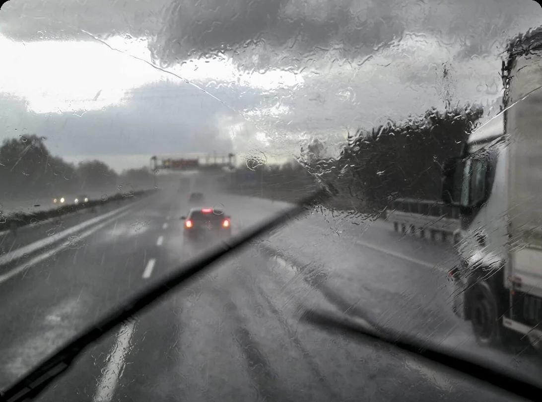 a view through a truck's windshield at a rainy highway