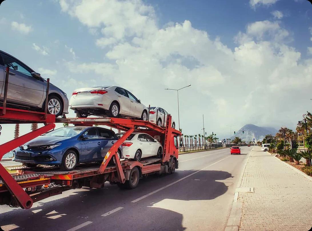 A car being loaded onto an open-air auto transport carrier for shipping