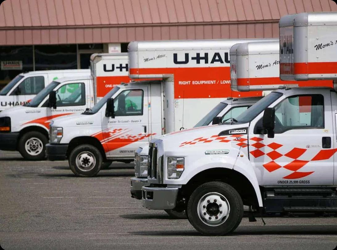 Uhaul trucks of different sizes are parked in a row in a lot