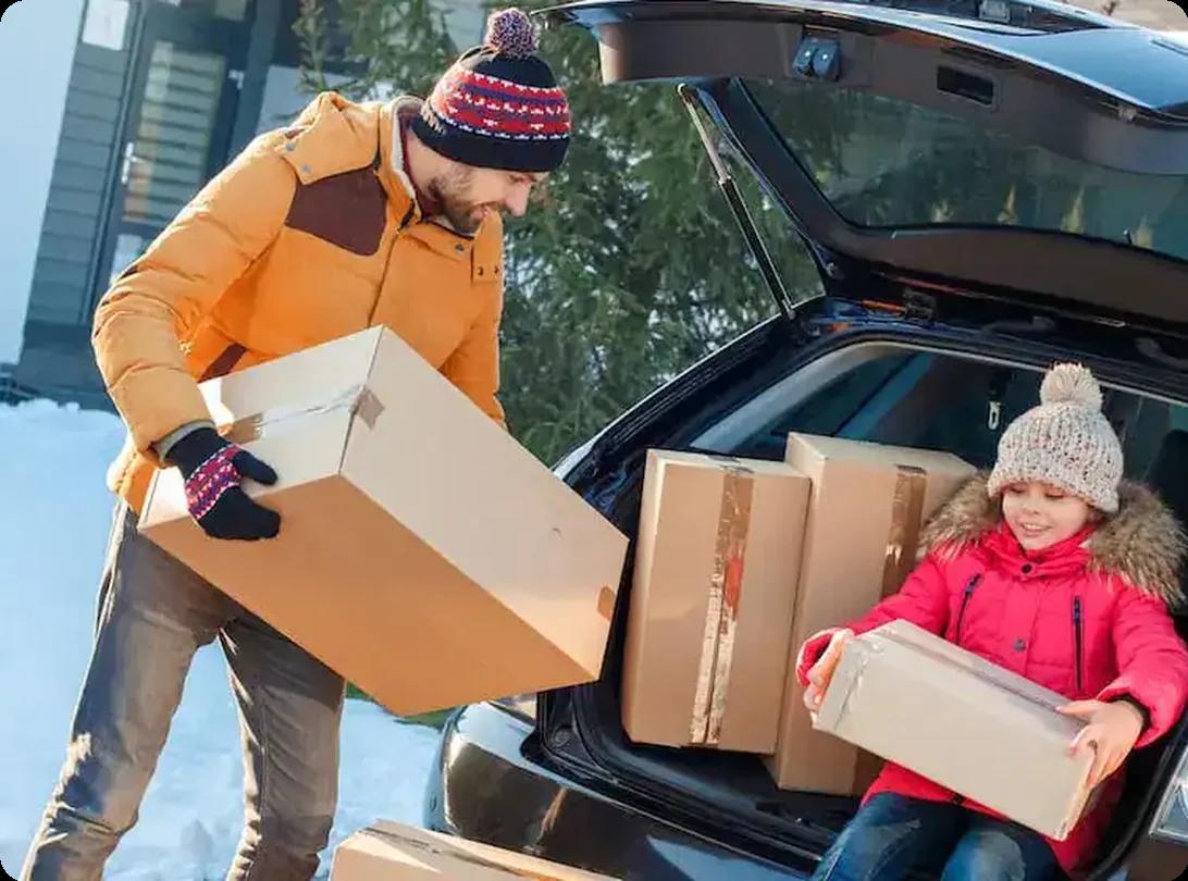 Family unloading moving boxes from a car during a winter move