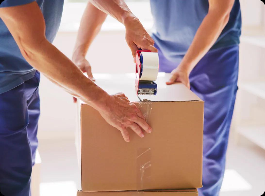 Mover packing a cardboard box during a move