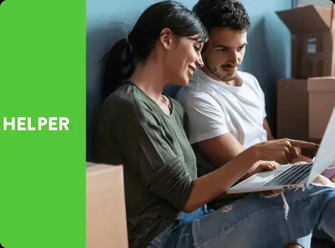 Couple sitting among moving boxes using a laptop to book movers on HireAHelper