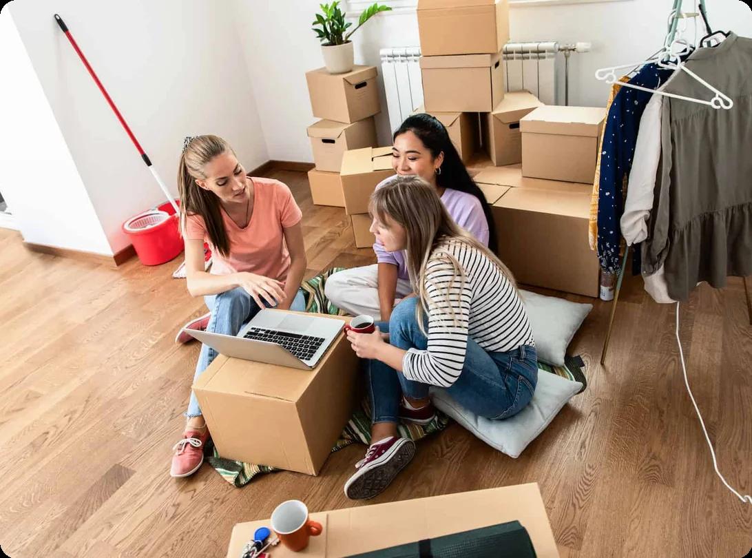 A group of young people sitting around moving boxes