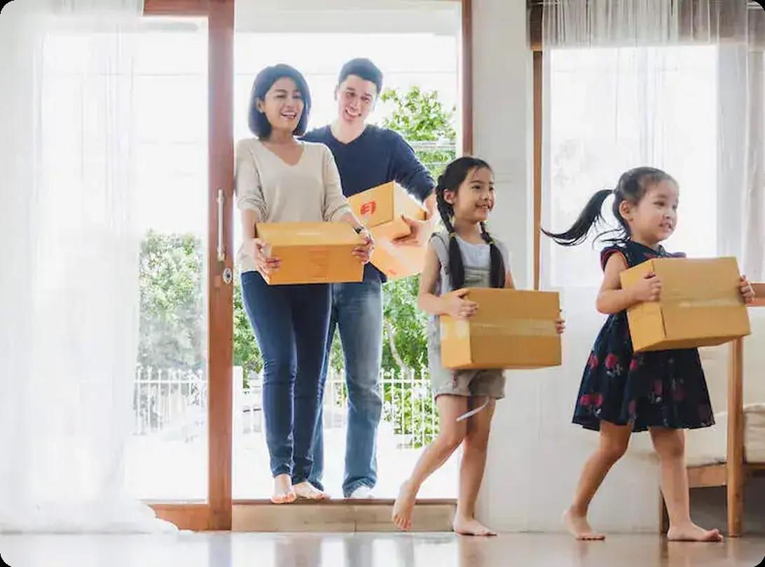 Happy family carrying boxes into their new home on moving day