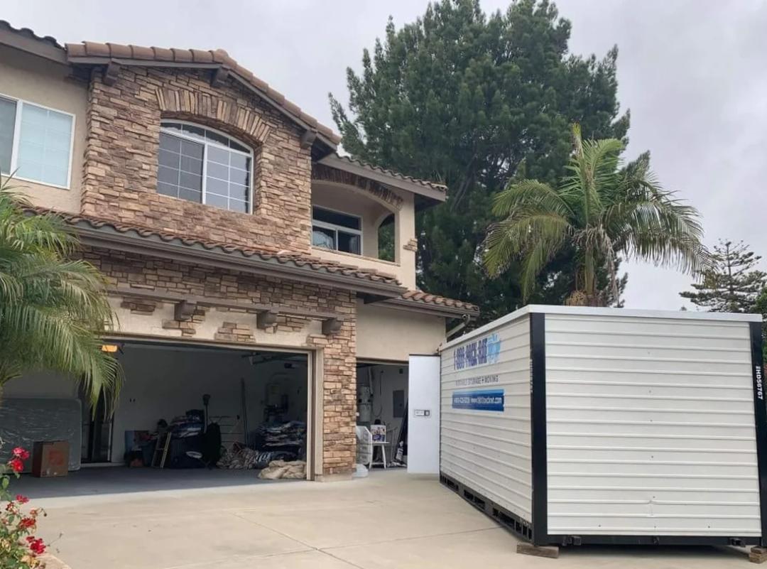a 1-800-pack-rat all-steel moving and storage container parked in a residential driveway