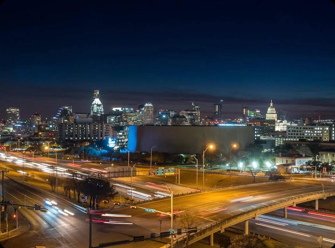 a view of traffic going by along highways at night near Austin, TX's downtown