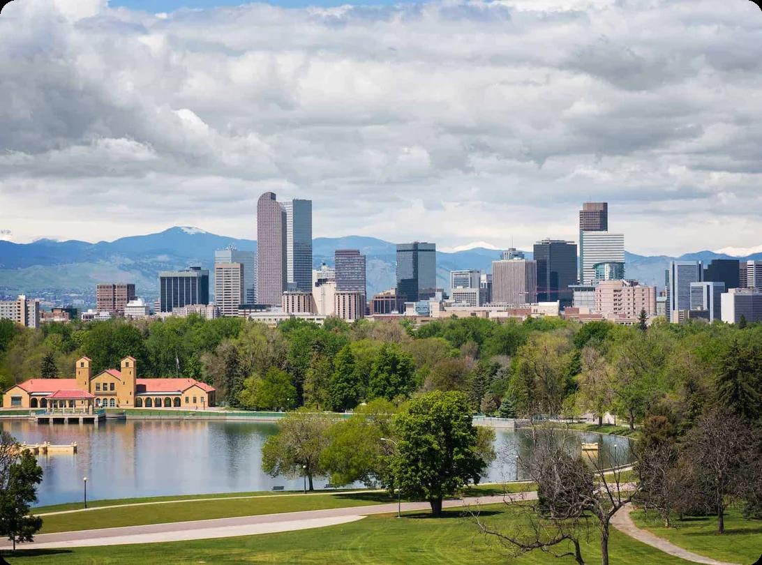 a view of downtown denver's skyline, a lake and park can be seen in the foreground