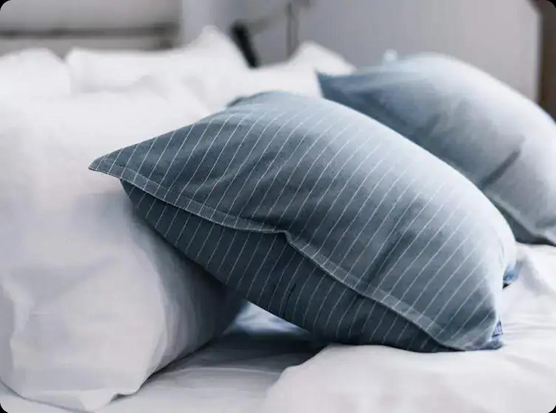 Stack of clean bed pillows arranged on a neatly made bed before packing for a move