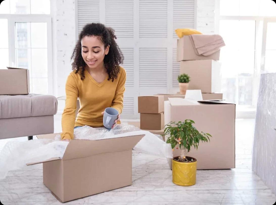A woman packs mugs into.a boxes filled with bubble wrap