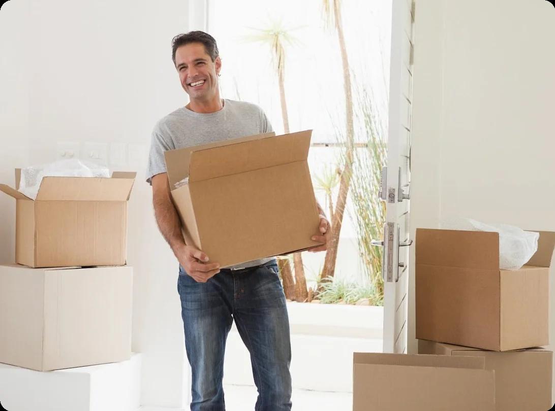 A man carries a moving box happily