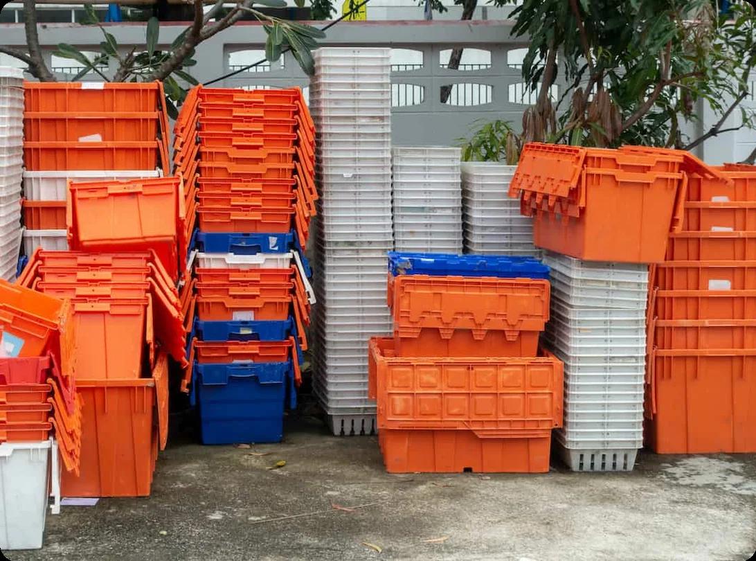A side-by-side comparison of stacked cardboard moving boxes next to durable reusable plastic moving bins
