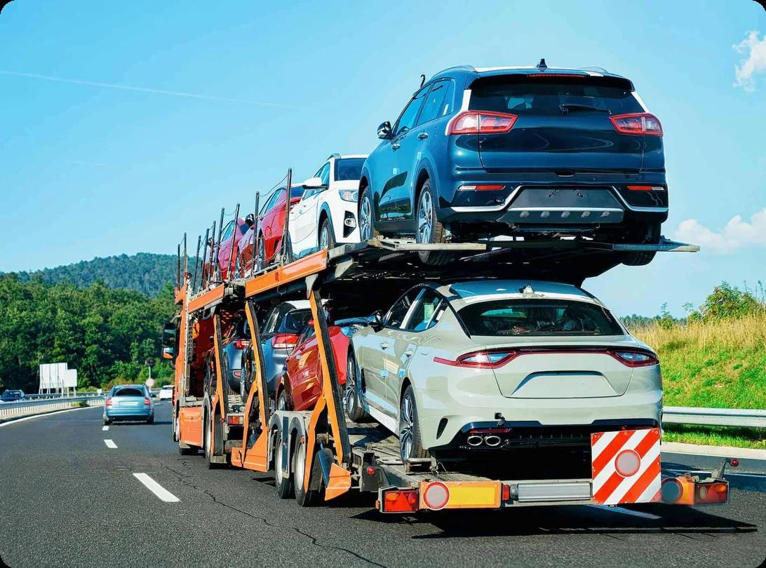 Two decks of cars being towed along a highway