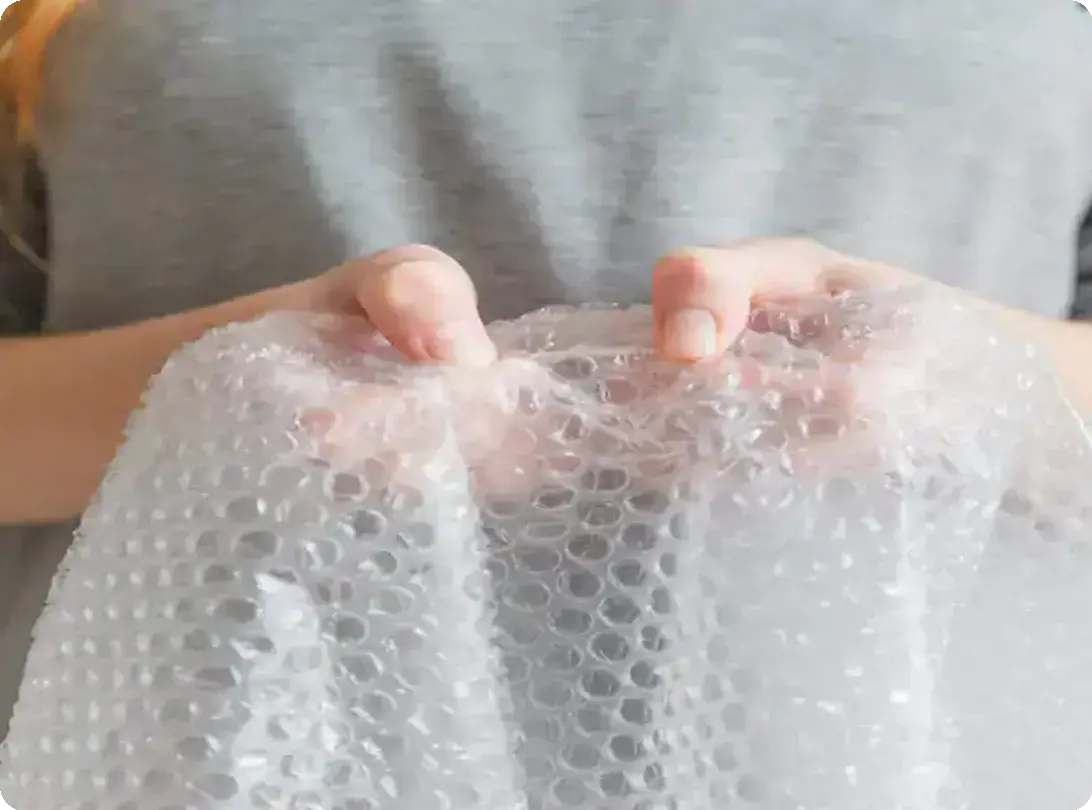 Close-up of a person holding a sheet of bubble wrap with both hands.
