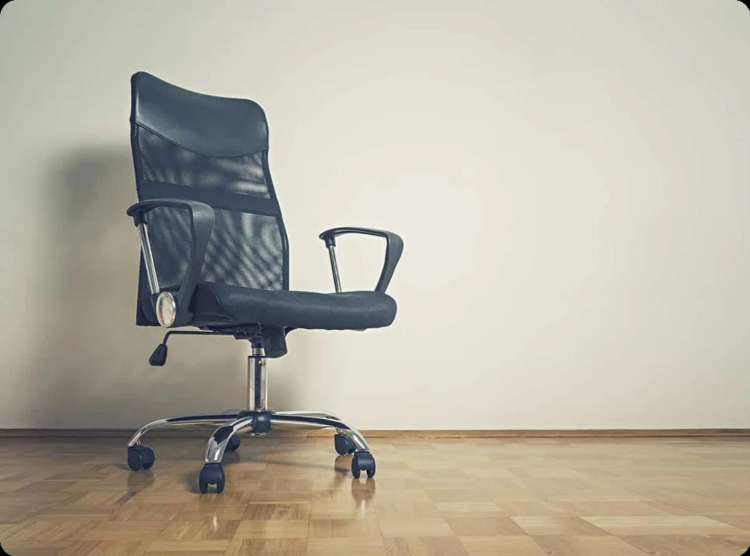 An office chair with armrests and casters being wrapped in plastic shrink wrap for safe moving and transport