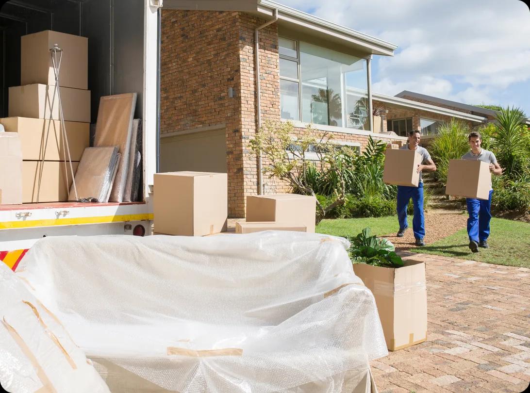 Movers carrying cardboard boxes from a house to a moving van