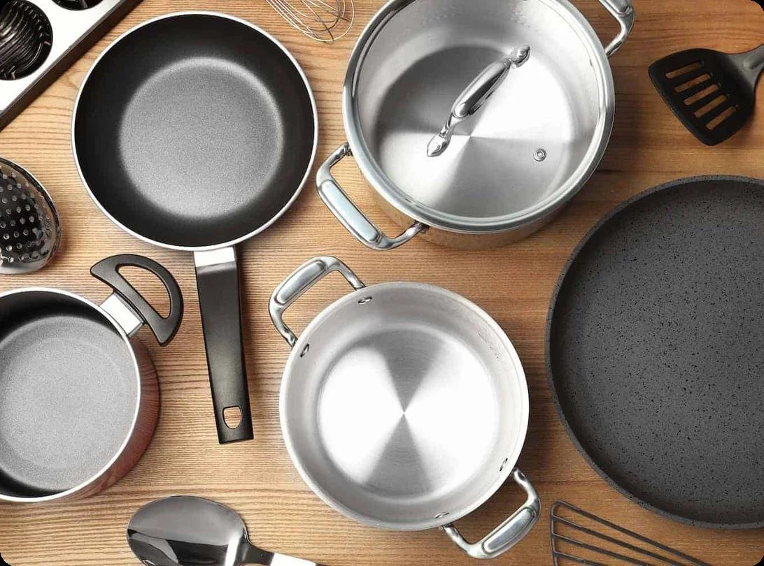 Stacks of pots, pans, and skillets being wrapped in packing paper and nested in a moving box