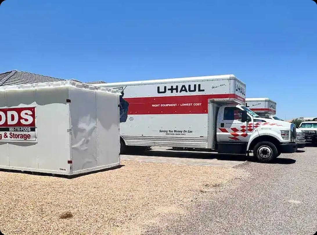U-Haul moving truck parked beside a PODS moving container in a residential neighborhood