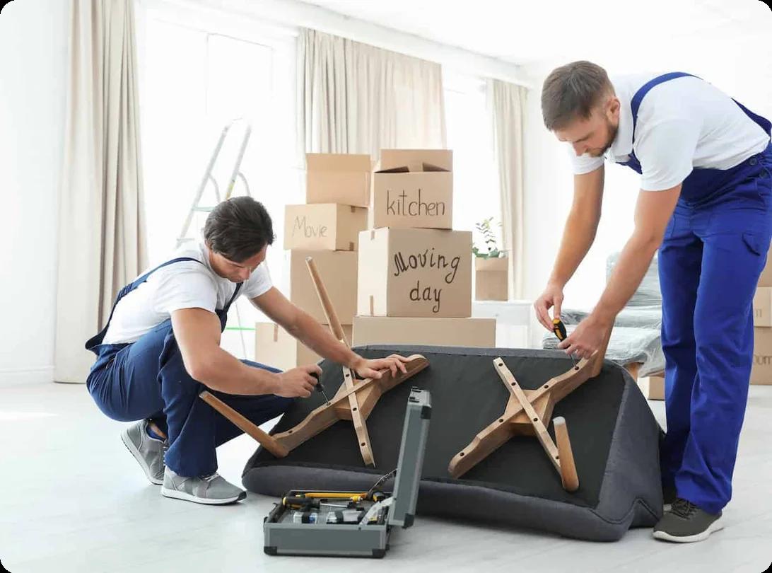 A professional mover using tools to disassemble a bed frame for transport