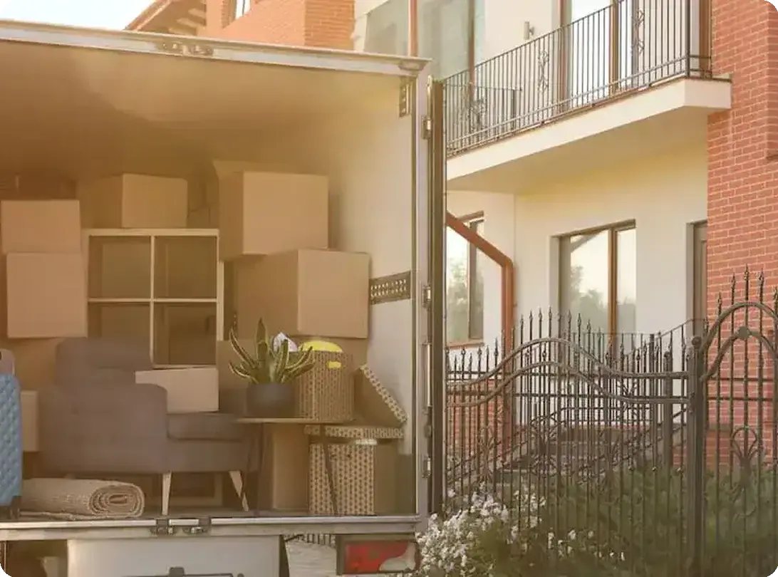 Open moving truck packed with boxes and furniture outside a house