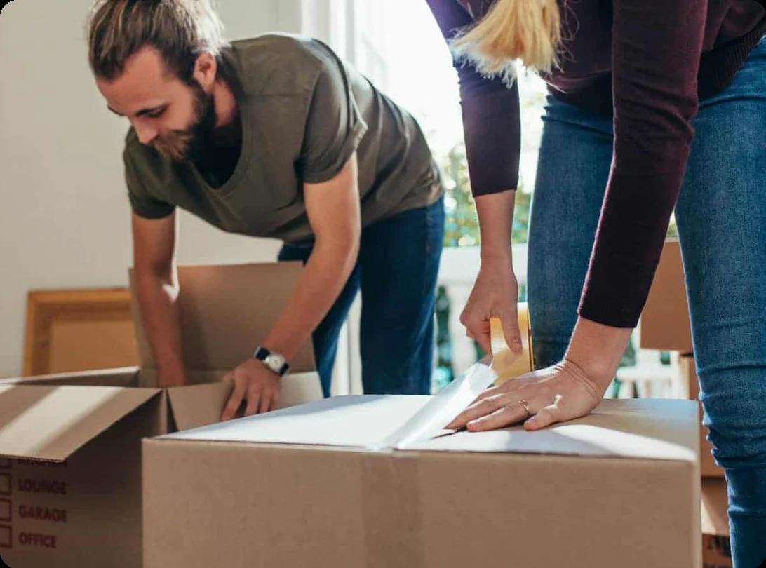 A couple works on packing and taping moving boxes shut