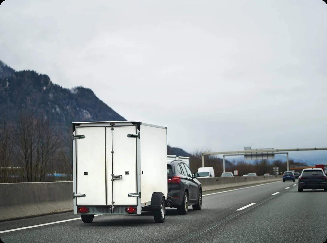 A car tows a cargo trailer down a highway