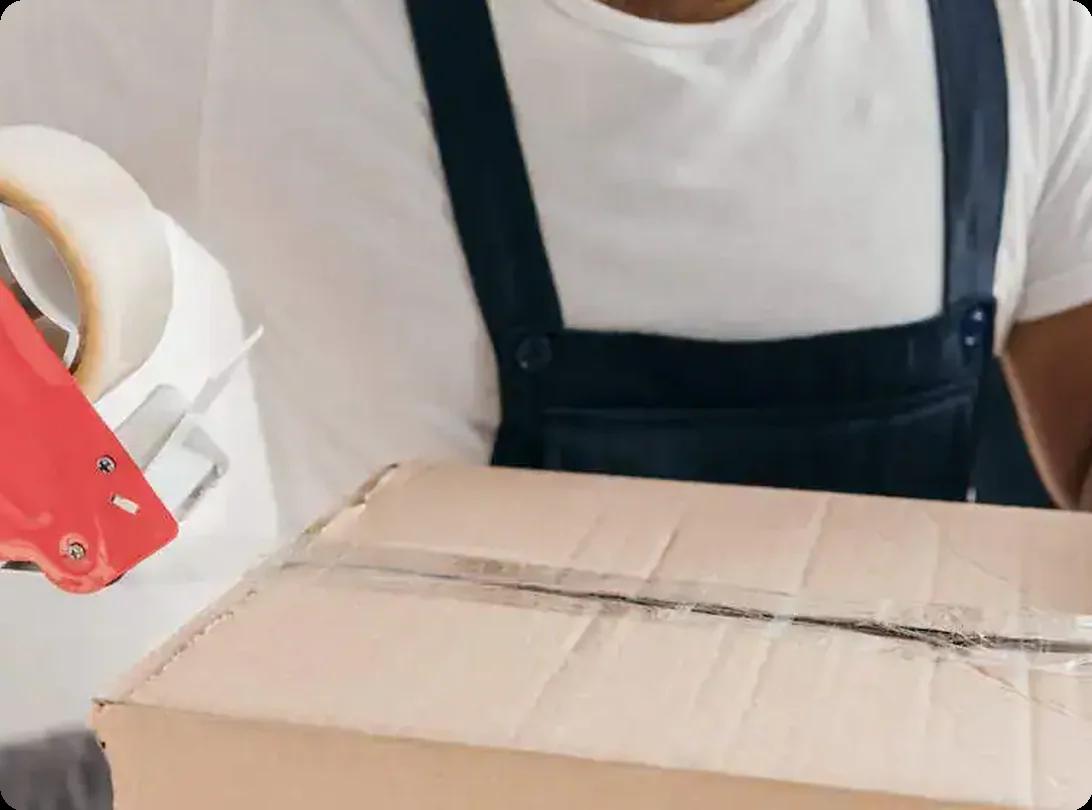 Professional movers packing cardboard boxes with tape for a move