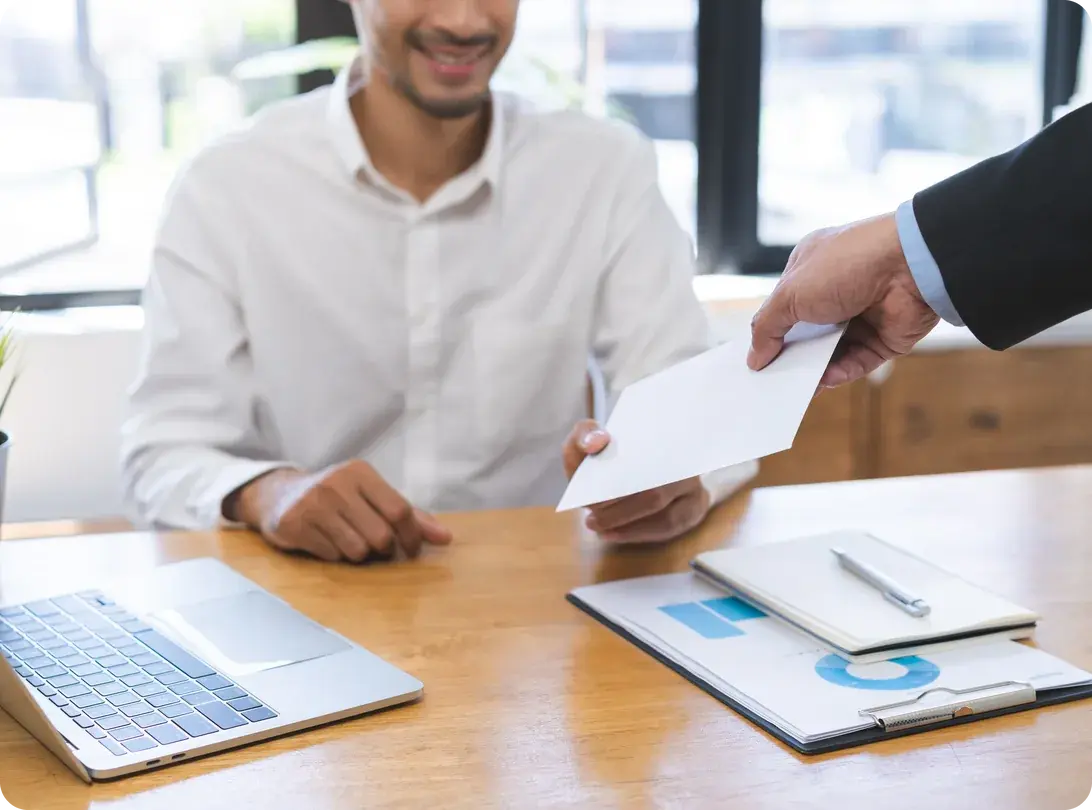 A hand receiving a cash bonus in an envelope