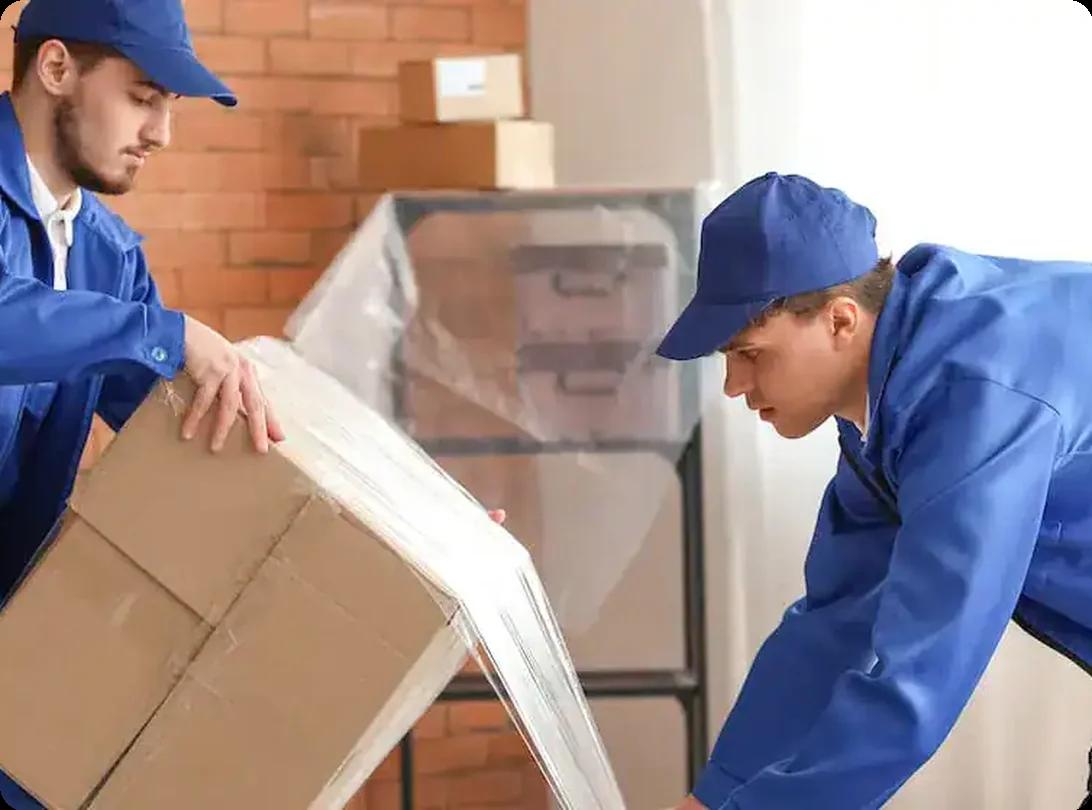 Movers in blue uniforms lifting and loading cardboard boxes indoors