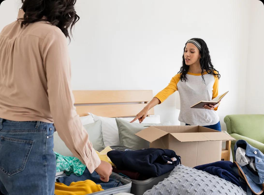 Mother and daughter organizing clothes into boxes in a bedroom