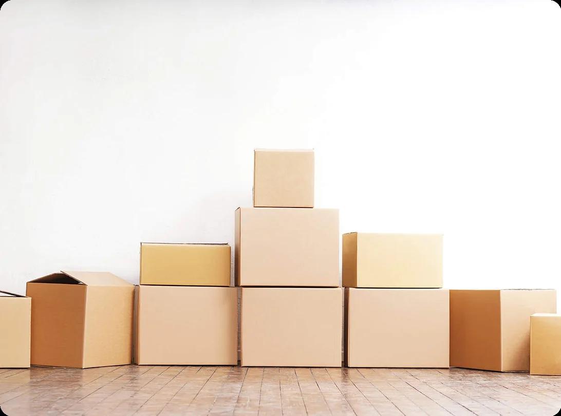 A close-up of hands carefully wrapping a fragile item in packing paper before placing it in a cardboard moving box