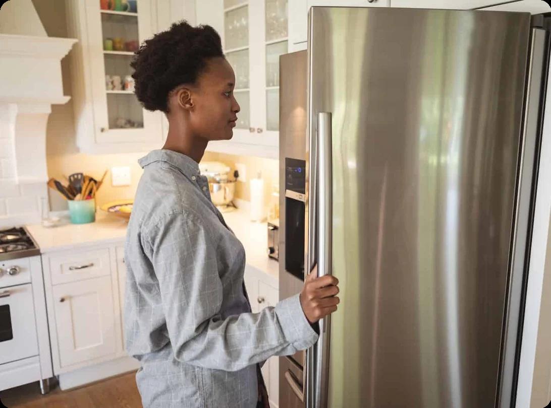 a woman looks into the fridge in her kitchen