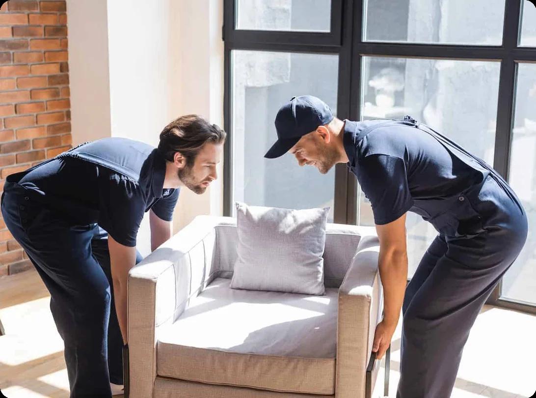 two movers work to lift a upholstered chair