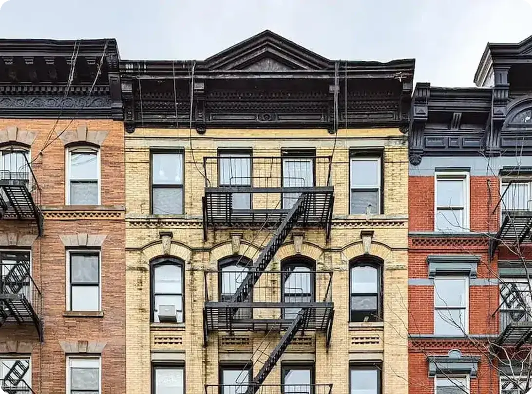 Historic apartment buildings with ornate facades and exterior fire escapes in a city neighborhood