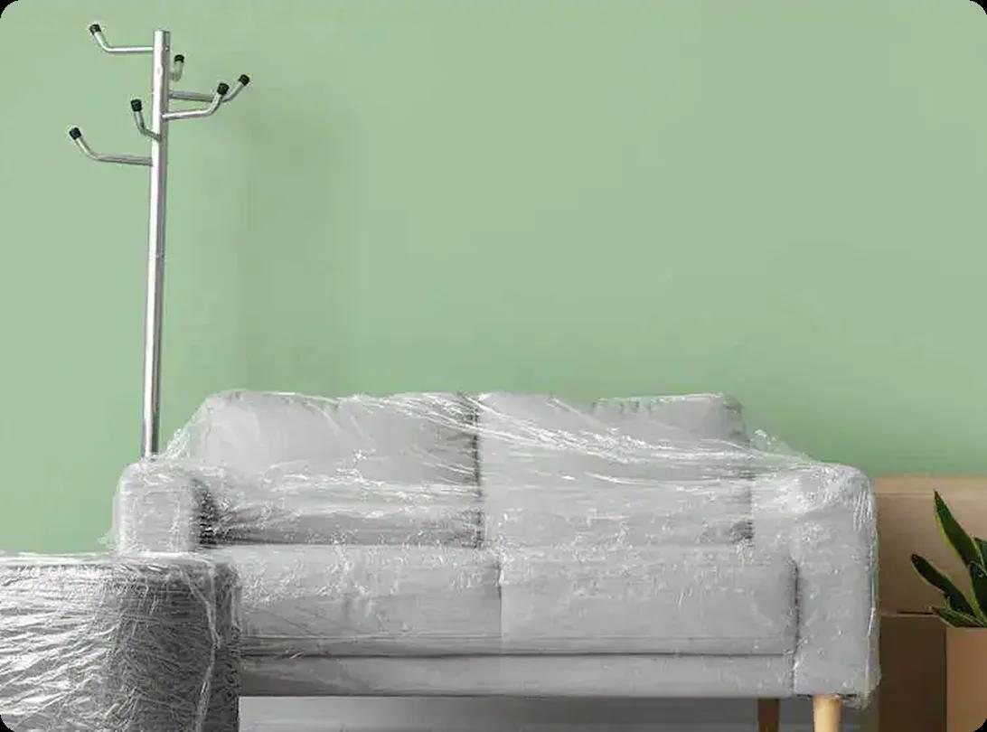 Sofa and furniture wrapped in protective plastic for moving.