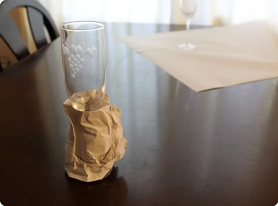 Stemmed wine glasses being individually wrapped in tissue paper and placed in a divided dish-pack box