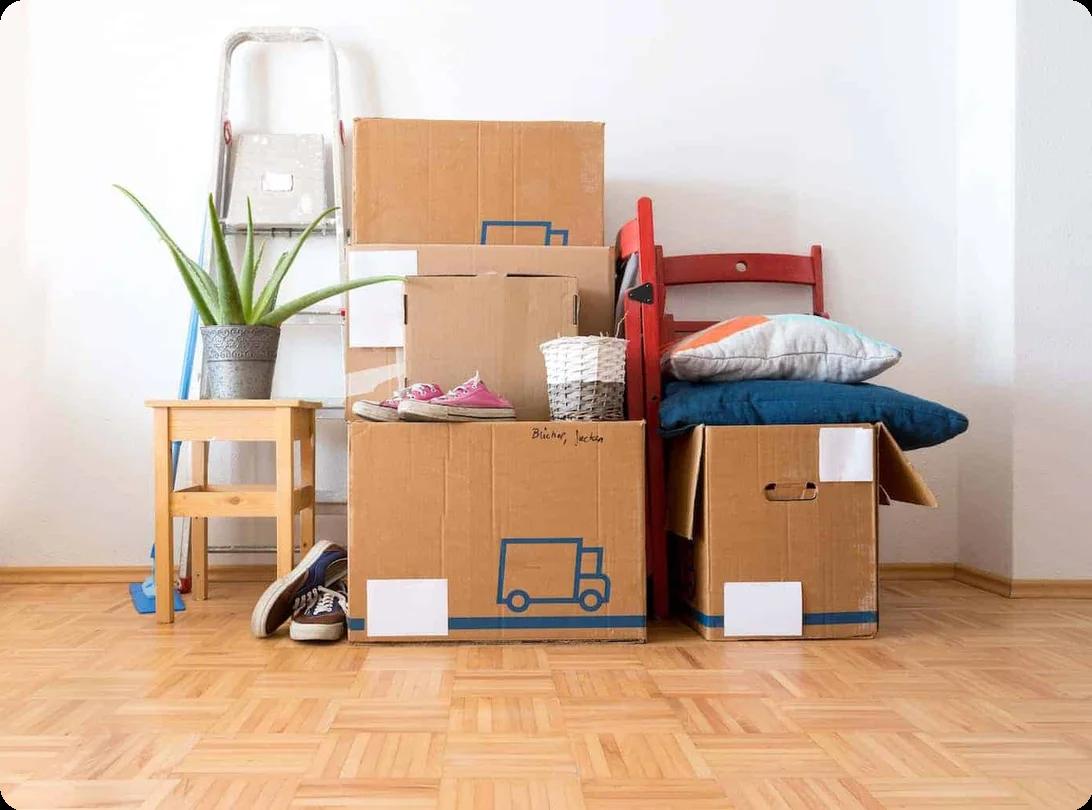 A pile of boxes filled with various items. Shoes and pillows are stacked on top of some of them