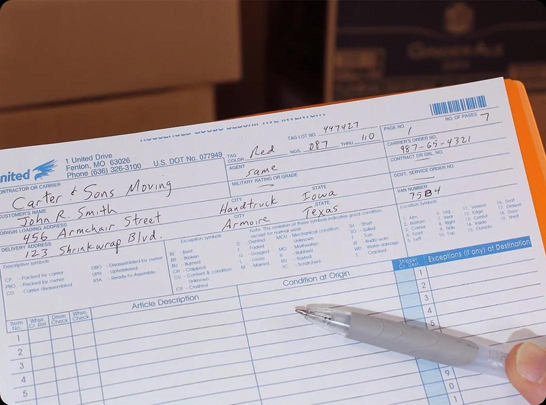 A person checking off items on a moving inventory clipboard next to a row of labeled cardboard boxes