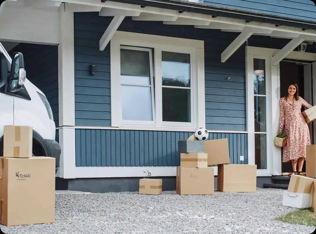 A couple carrying boxes out of a house to a waiting moving truck