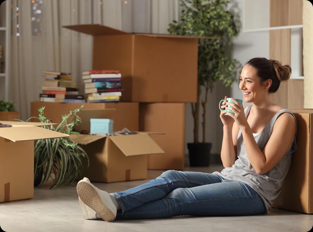 A happy person relaxing with coffee among moving boxes at a new home