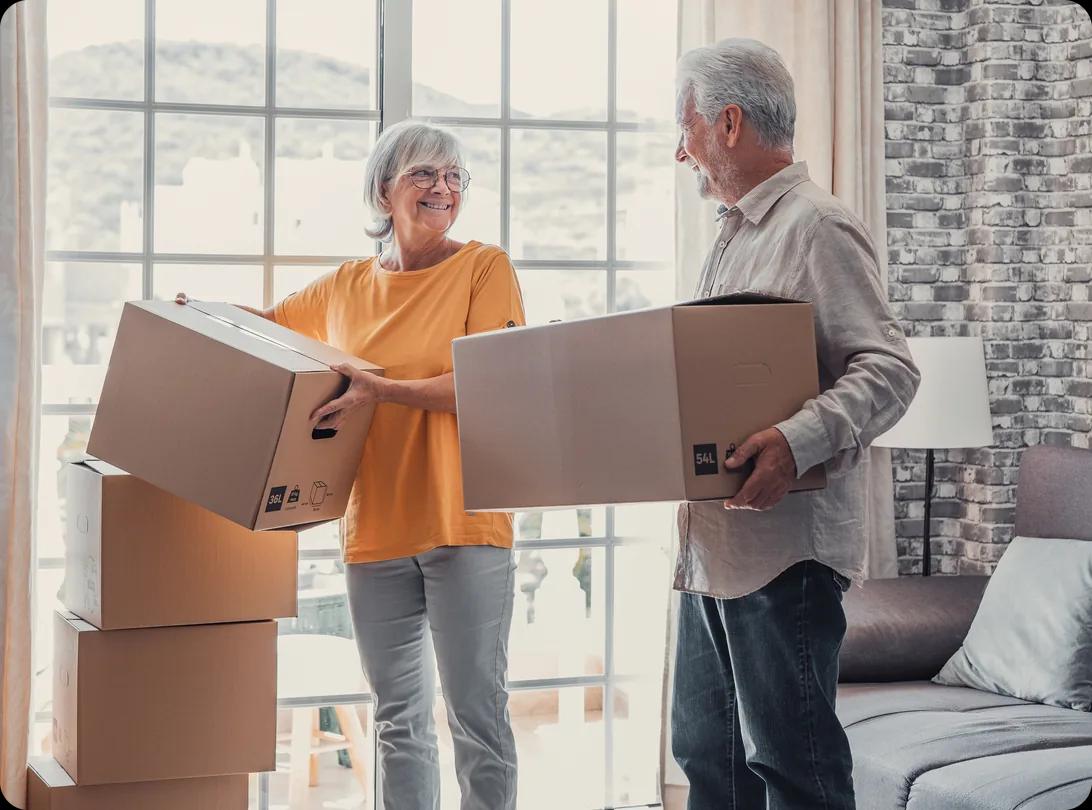 Mature couple moving into a new apartment carrying cardboard boxes