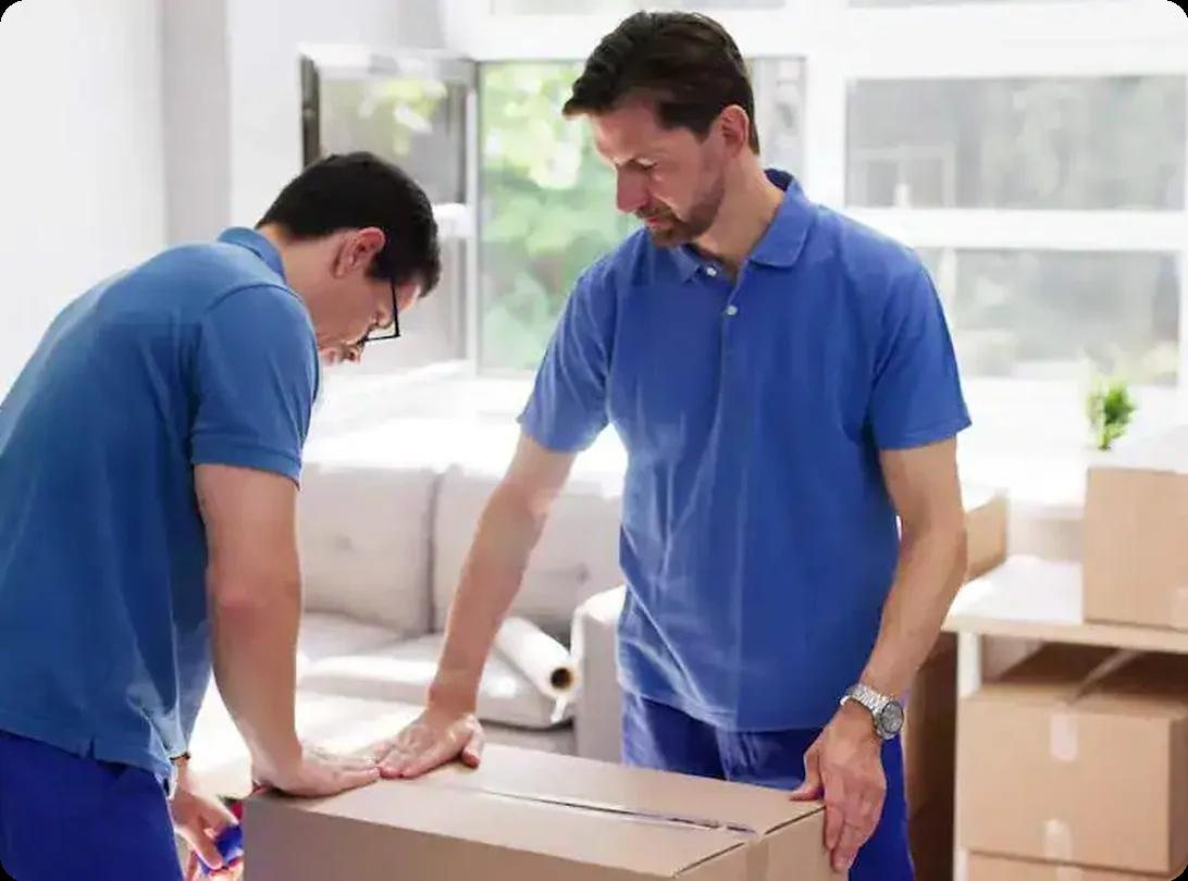 Movers sealing and packing household items into cardboard boxes for a move