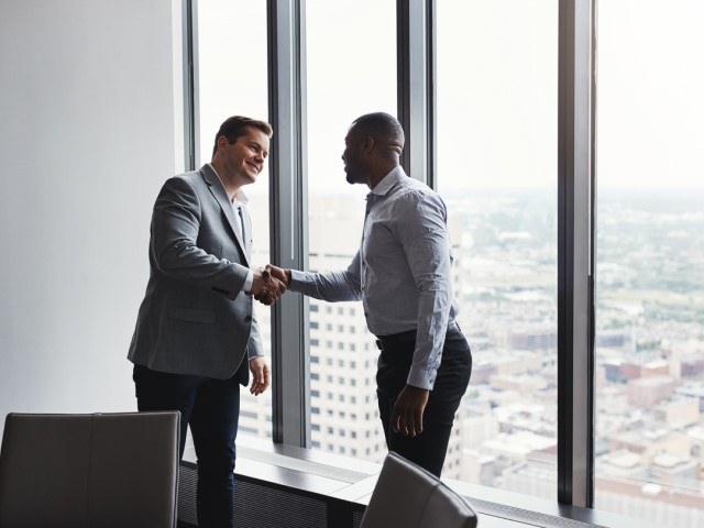 Two people shaking hands in an office building.