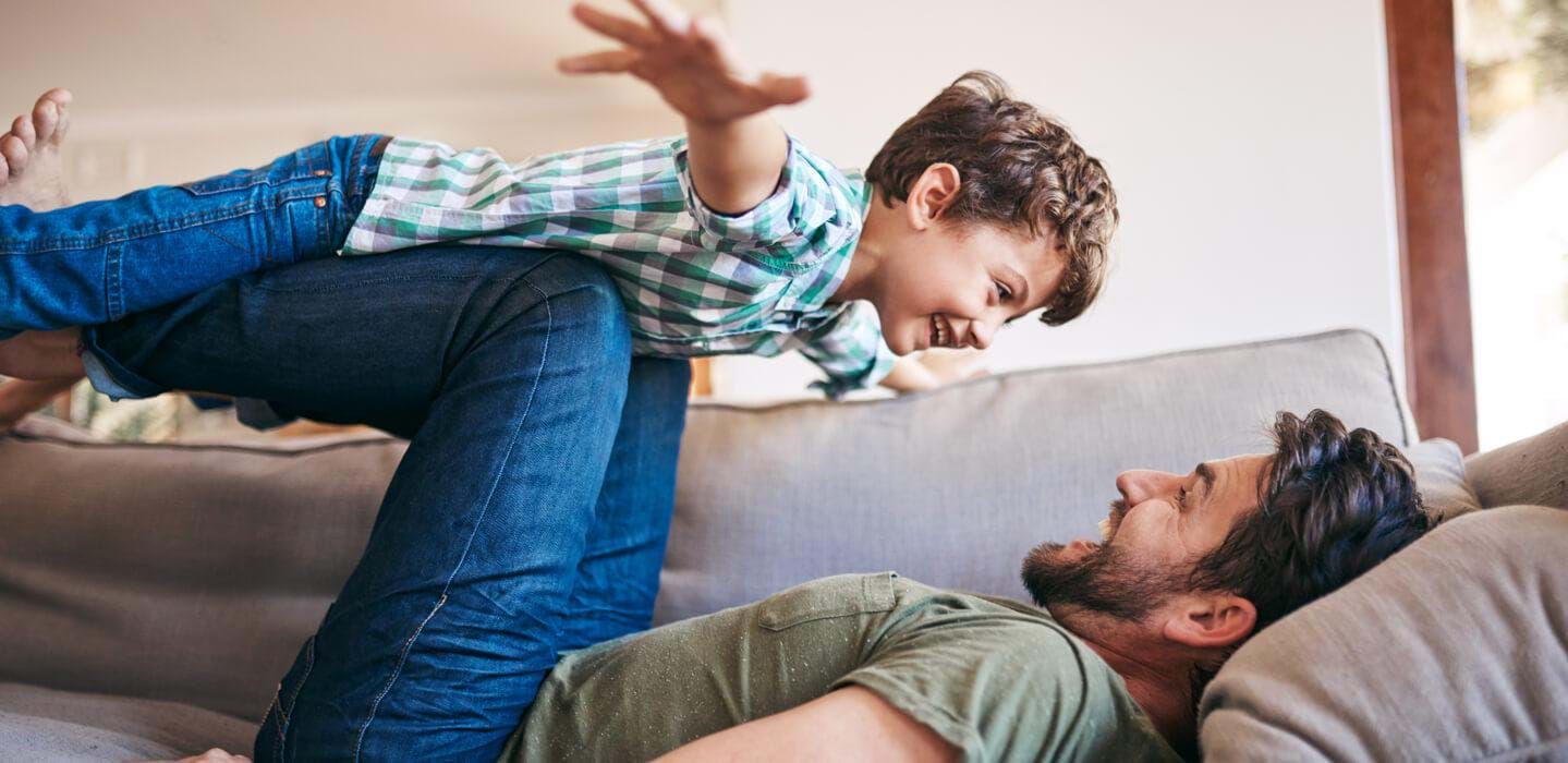Man smiling lifting smiling child over him