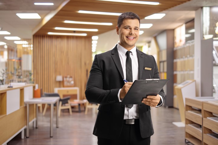 Man holding clipboard with suit on in a lobby