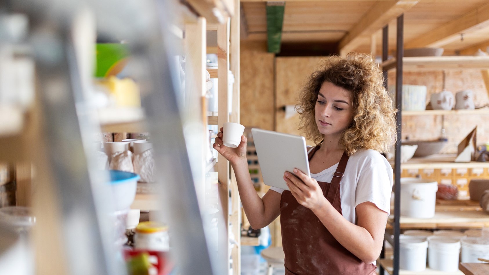 Person holding a small cup looking at a tablet