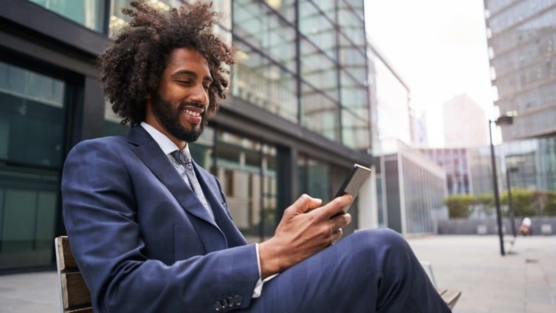 Man sitting on a bench smiling looking at his phone