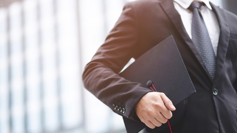 Person in a suit holding a graduation hat
