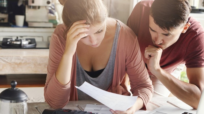 Couple looking at papers with hand on forehead