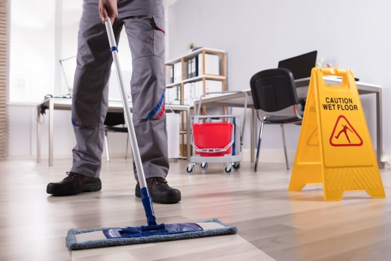 A janitor mopping the floors of an office space